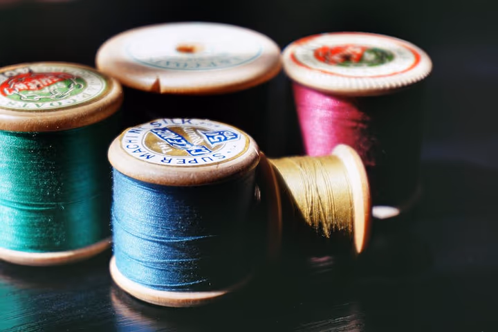 Bobines de fil à coudre colorées en bois, alignées pour des travaux de couture et artisanat.